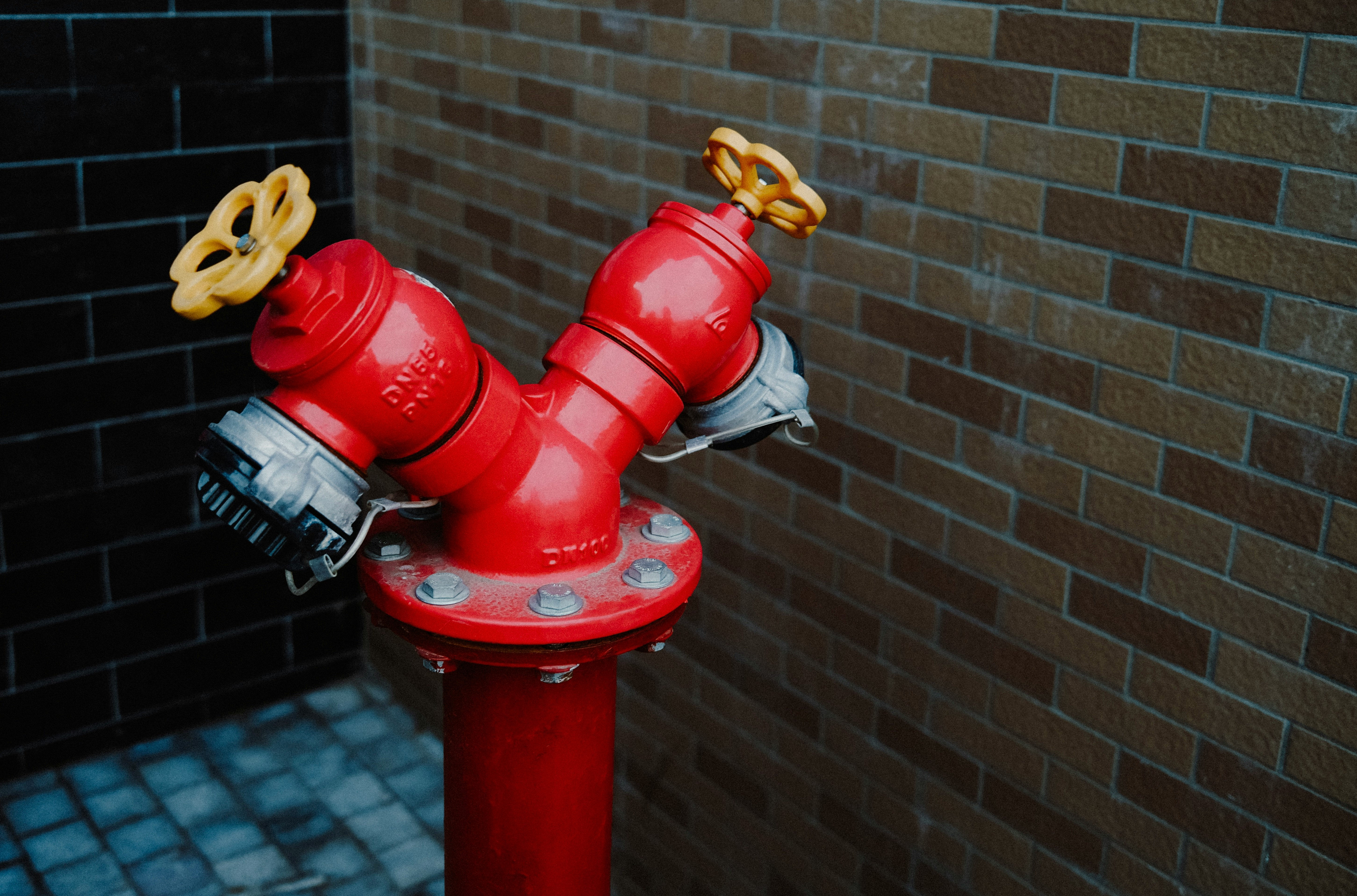 red fire hydrant near brown brick wall